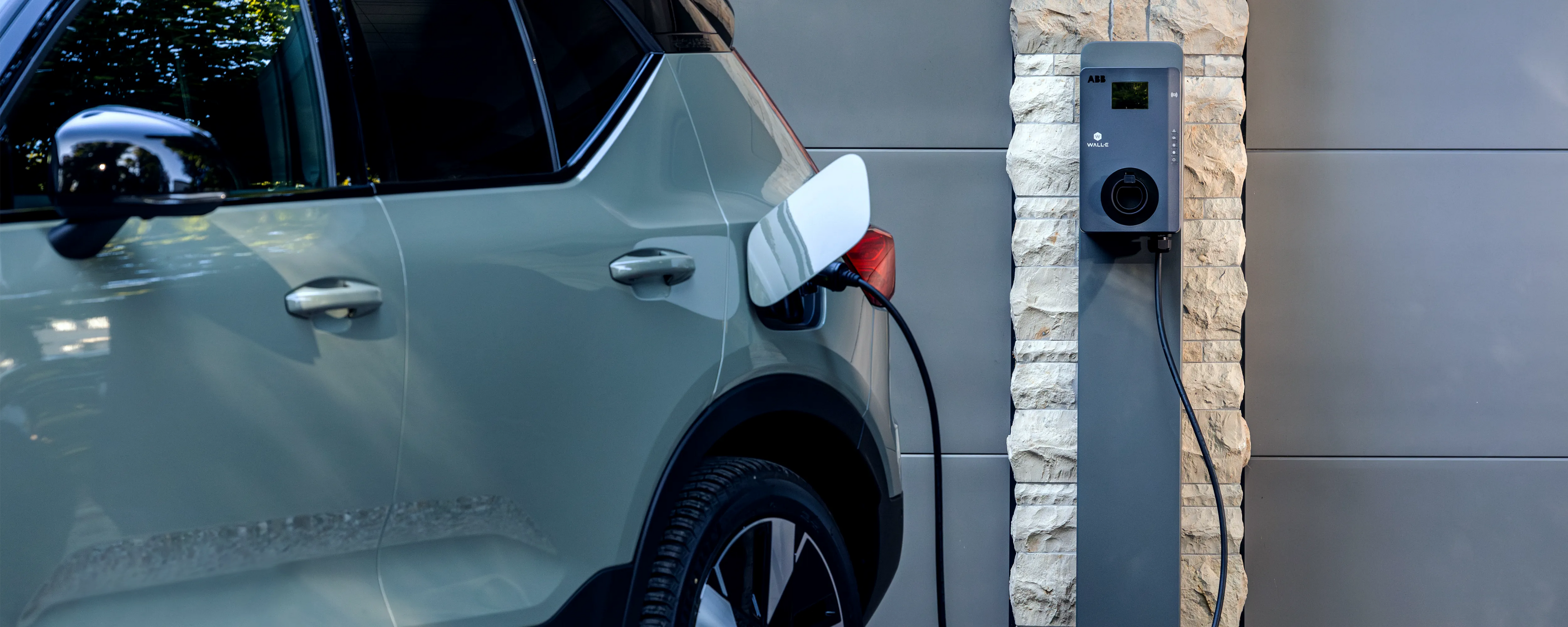 Ein Volvo Elektrofahrzeug steht vor einer Garage und lädt an einer WALL-E Premium Wallbox 